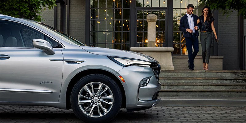 Buick Enclave ready to pick up two people leaving from a building
