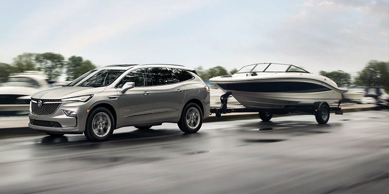 A Buick Enclave hitching a boat and driving down the road