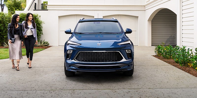 Two women admiring a New 2024 Buick Encore GX sitting on the driveway