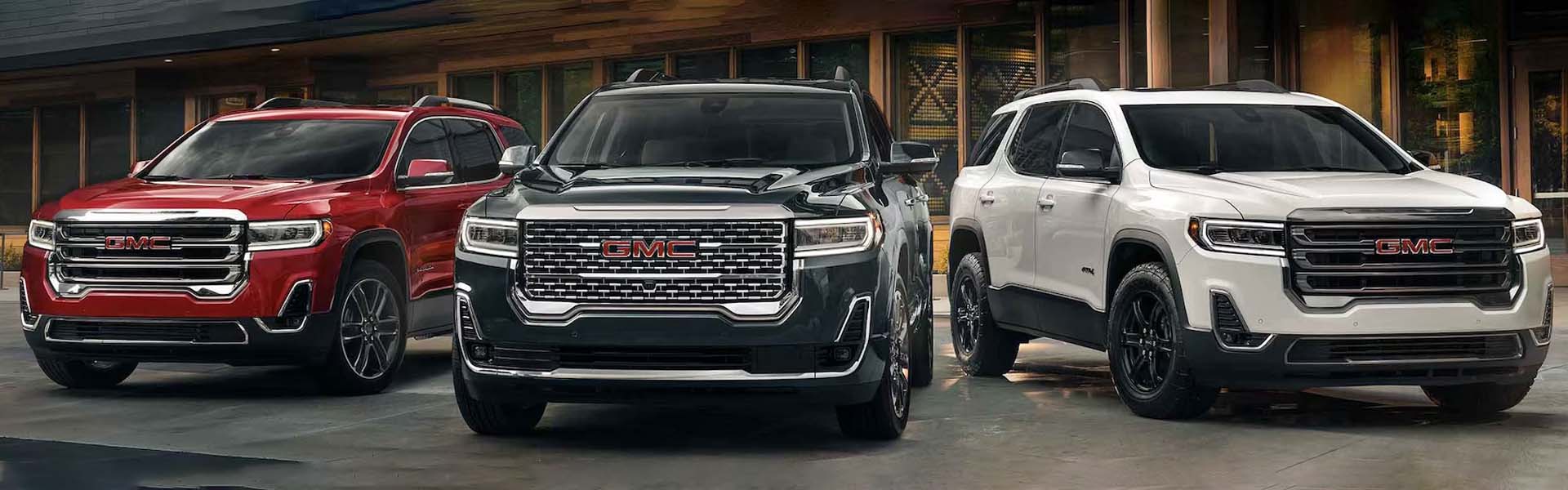 3 2023 GMC Acadia vehicles outside in front of a building