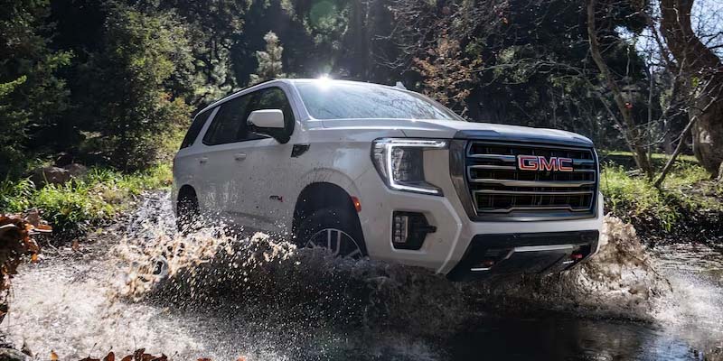 White GMC Yukon driving through a lake