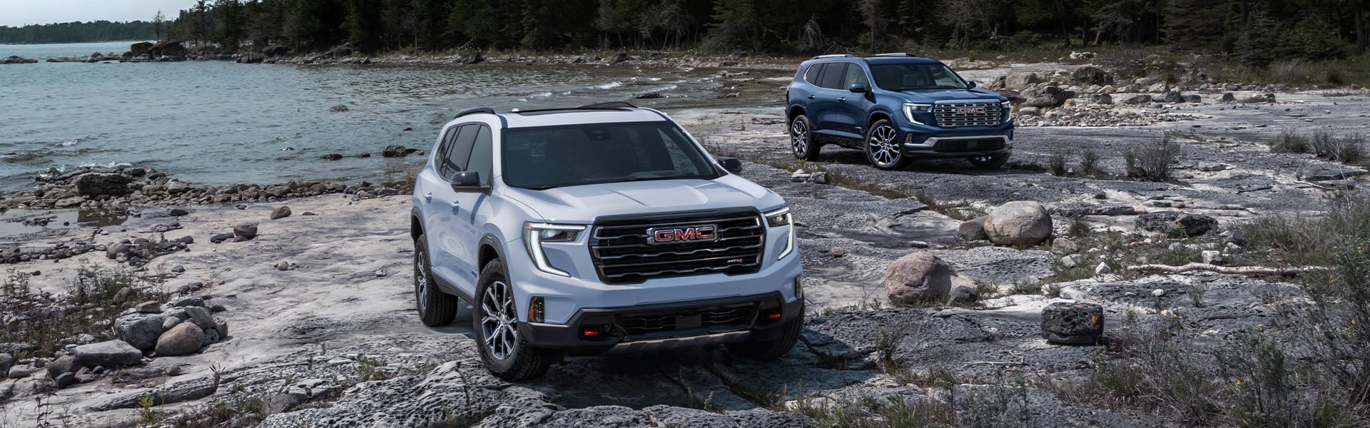 2 2024 GMC Acadia vehicles near a lake